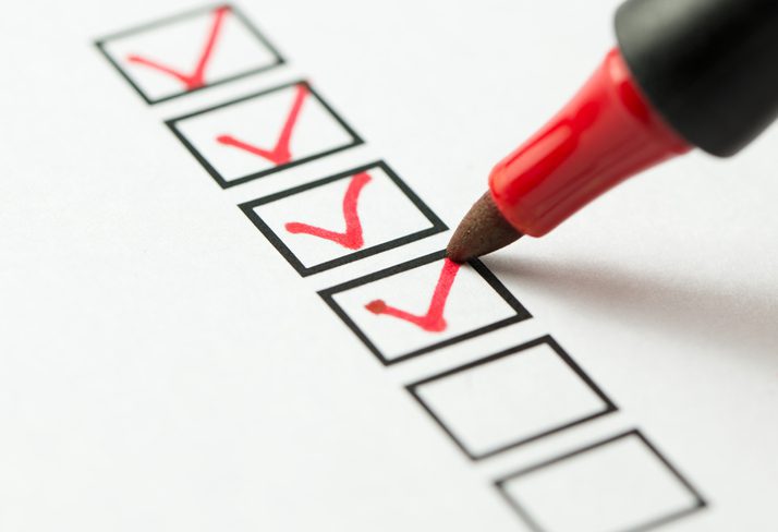 Red marker checking off black boxes ERP implementation project checklist