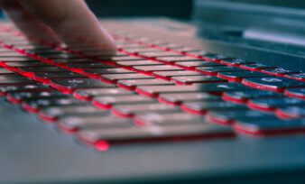 Hands typing on backlit keyboard