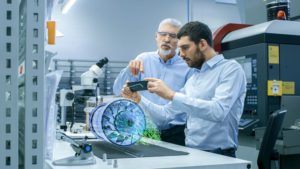 Two men in a lab working and looking at a cell phone.