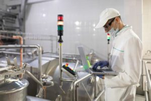 man in food manufacturing plant looking at laptop