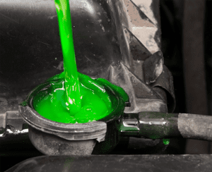 Green substance being poured into a mechanical recpetacle.
