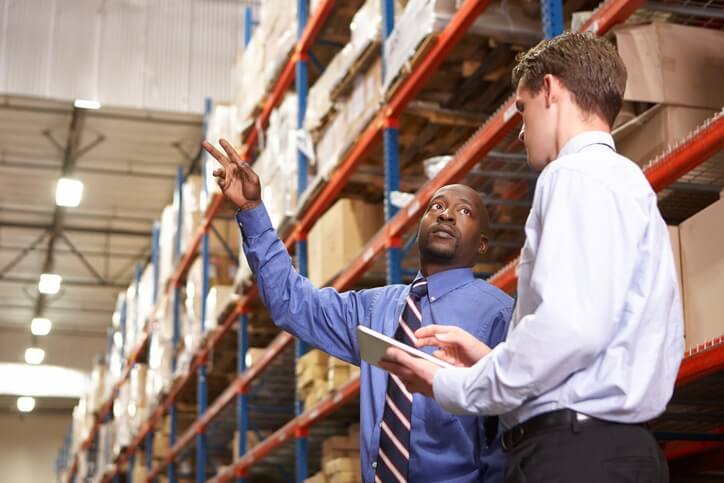 Two business men talking in a warehouse setting.