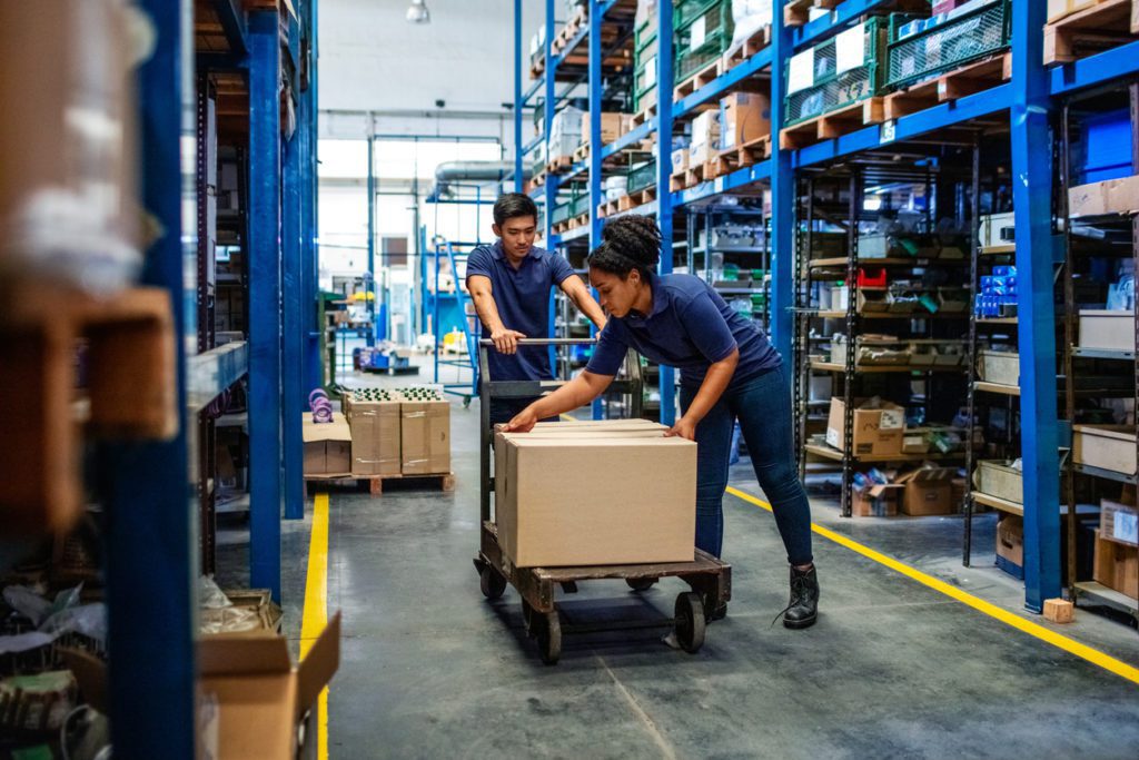 Man and woman in a warehouse putting boxes on cart