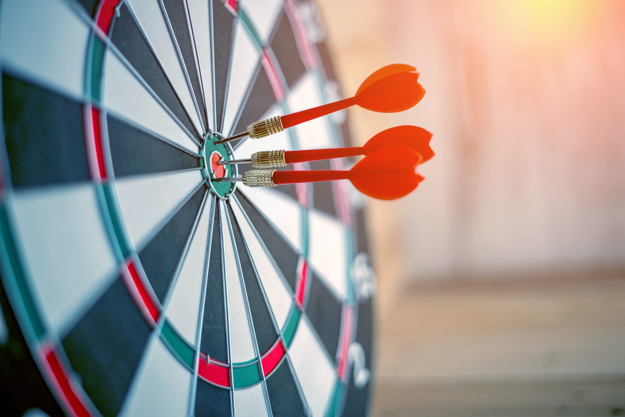 Red dart arrow hitting in the target center of dartboard business success ideas concept