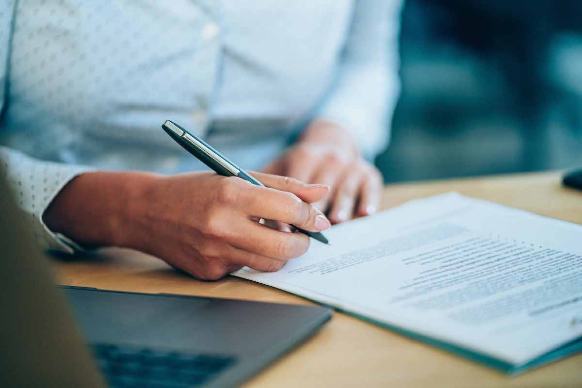 Woman with pen in hand signing contract