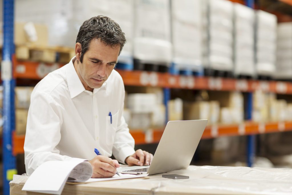 Man working on a laptop in a warehouse procure to pay consultant